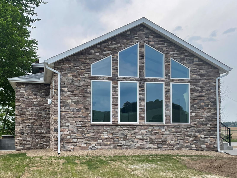 Custom great room with stone exterior and prow window wall by Stellar Construction