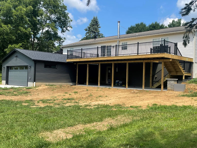 New custom home rear elevation with raised deck and attached garage by Stellar Construction